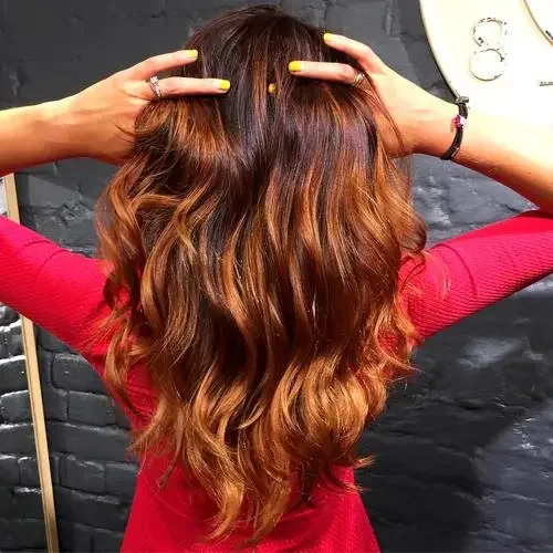 Deep brown hair with warm copper ombre and long loose waves.