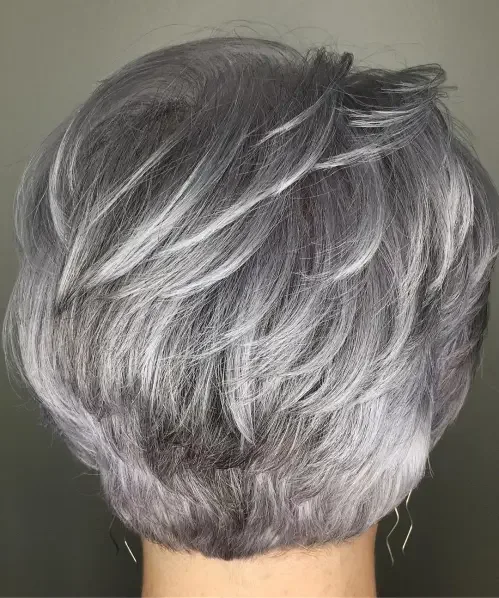 Silver-gray feathered pixie with swooped side fringe and tapered wedge shape.
