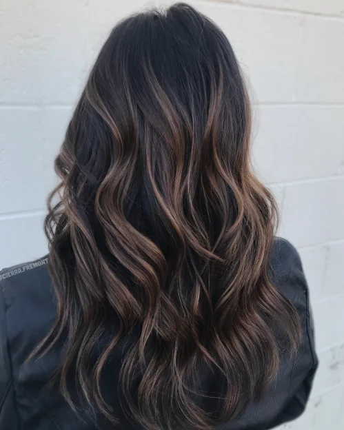 Long layered waves with an espresso brown base and warm brown balayage streaks for dimensional shine.