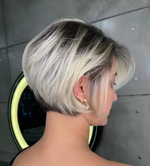 Smoky ash-blonde bob with thin angled fringe and compact rounded shape