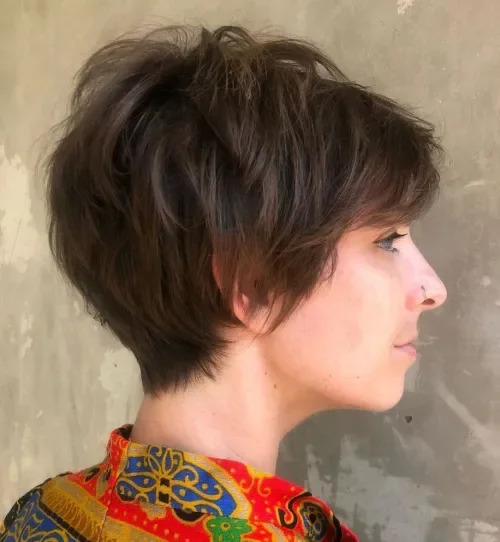 Tousled pixie crop with side-swept fringe and textured, matte finish in medium-dark brown.