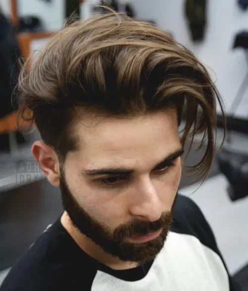 Messy wavy dark brown top with a low fade undercut and side-swept volume.