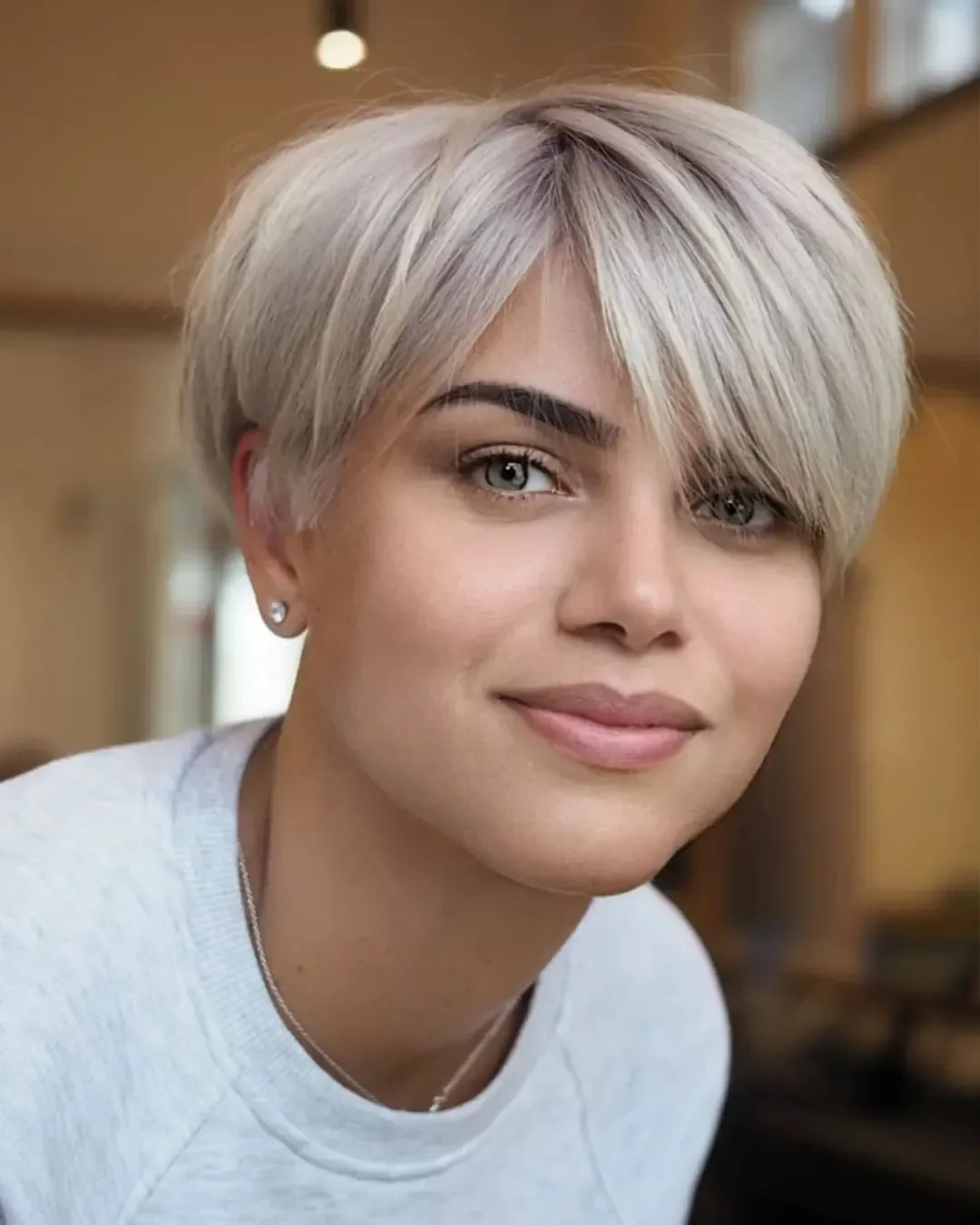 Short pearl blonde bixie with forward-swept fringe and wispy textured layers