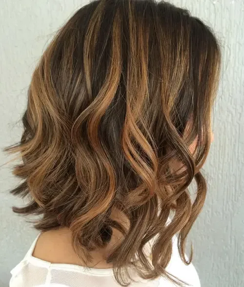Medium-long wavy hair with rich brown base and warm caramel ribbon highlights