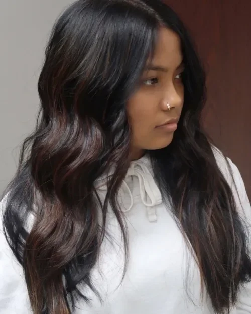 Long black hair with loose waves and dark red highlight ribbons through mid-lengths and ends.