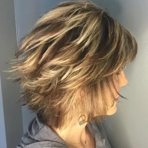 Feathered layered shag crop with side-swept fringe and warm light brown hair with blonde highlights