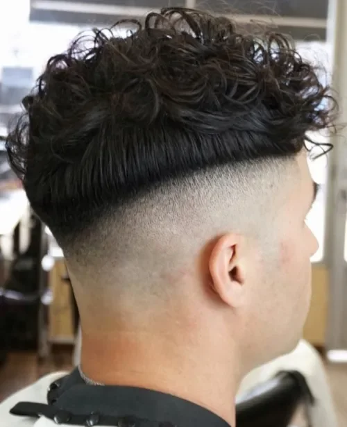 Skin fade with a curly top combed up and forward