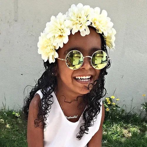 Long tight ringlet curls with a white flower crown and off-center part.
