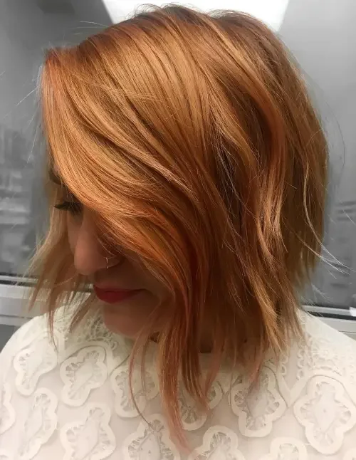 Chin-length strawberry red bob with choppy layers and caramel undertones