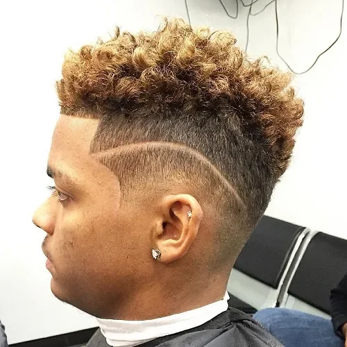 High fade with a curved line detail and voluminous curly top in warm dark tones with lighter blond curls