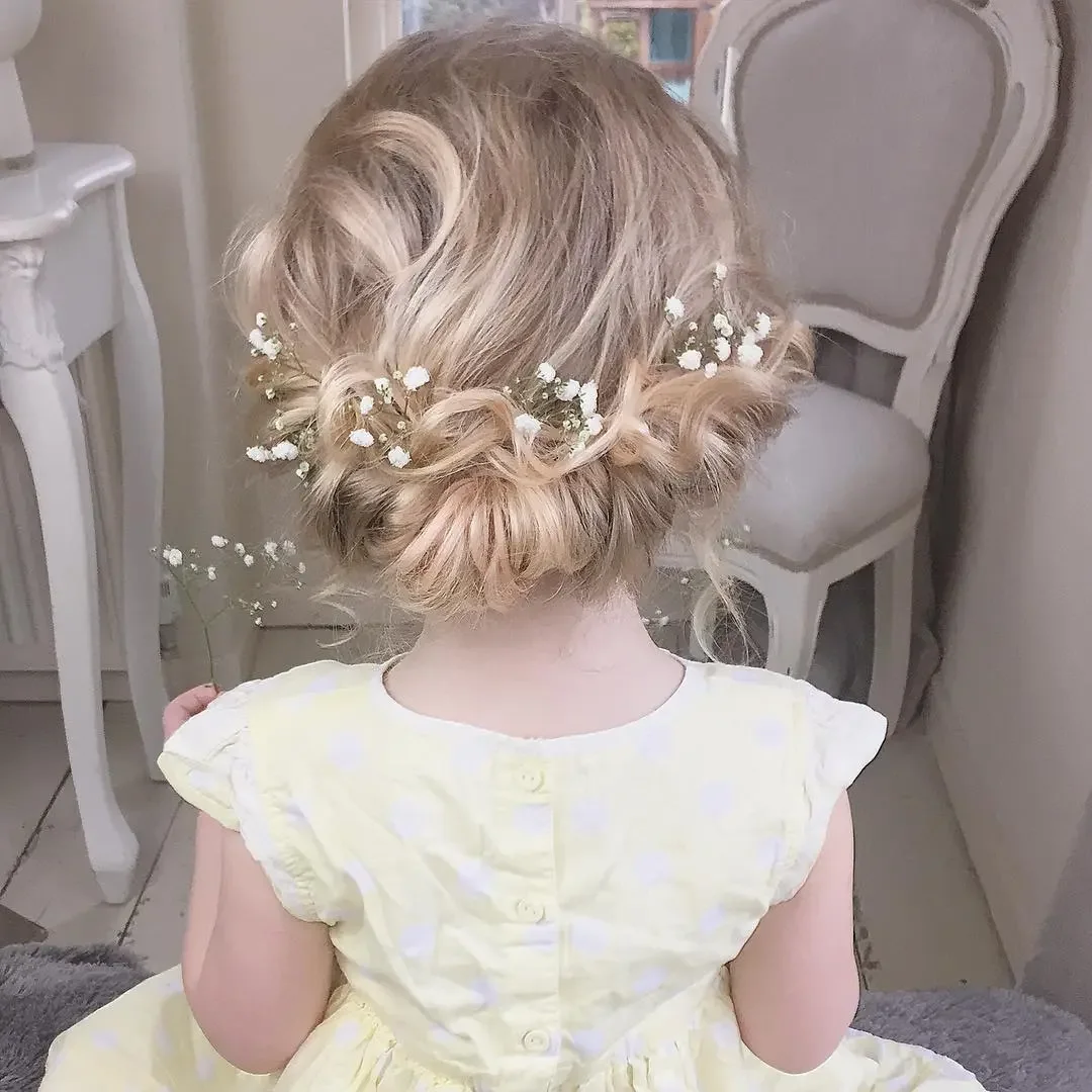 Curly chignon updo with small white flower clips and soft volume