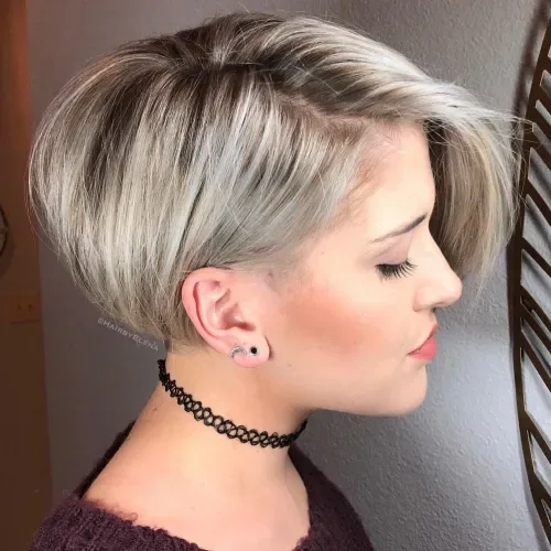 Neat ash blonde bixie with side part, longer swept top, and subtle silver highlights.