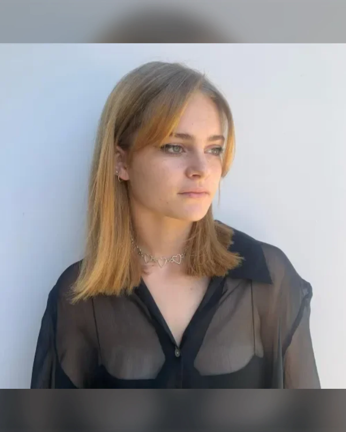 Blunt crop haircut with long straight bangs and dark blonde hair, shown smooth and even at the ends.