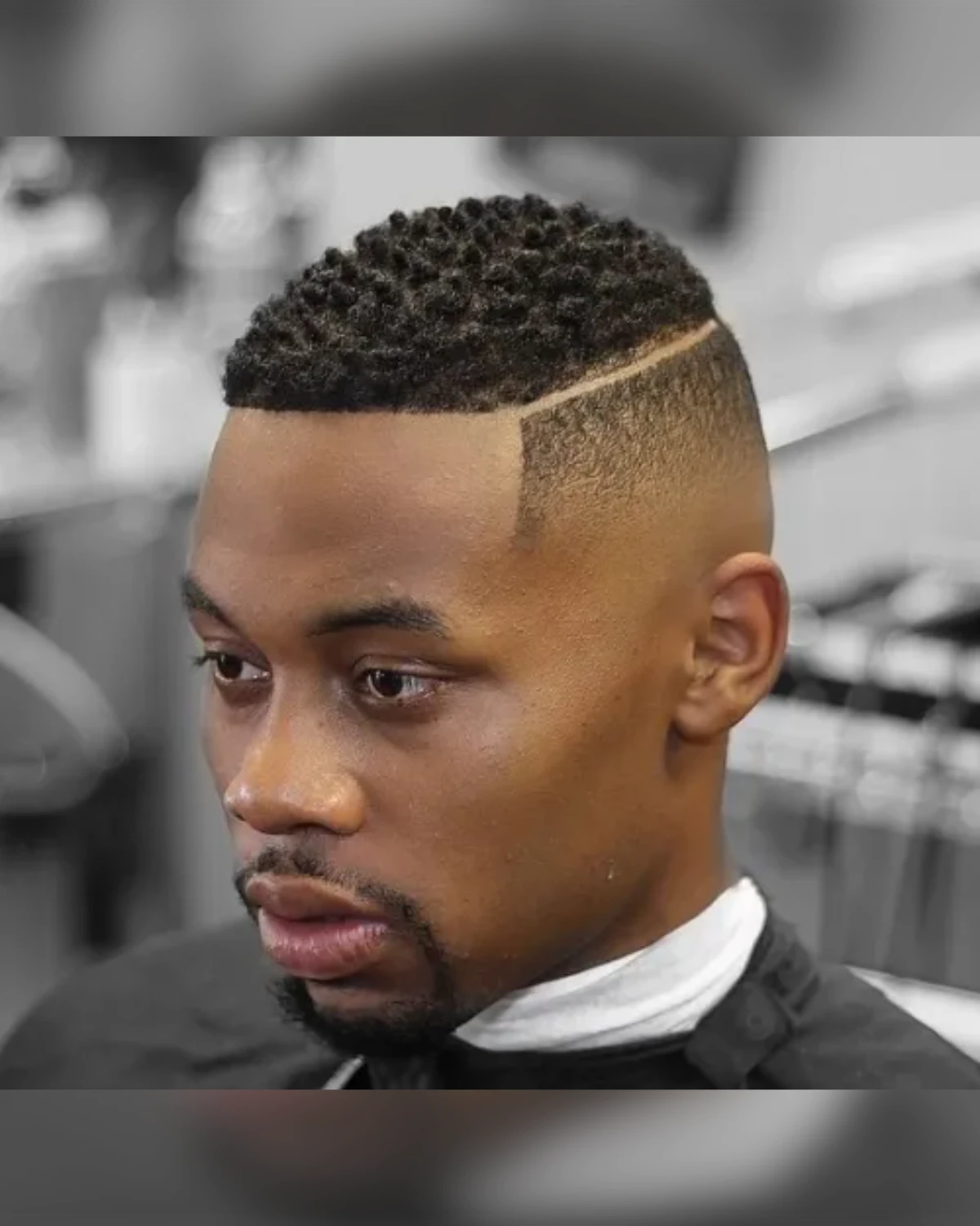 Bald fade with a shaved side part and short curly top
